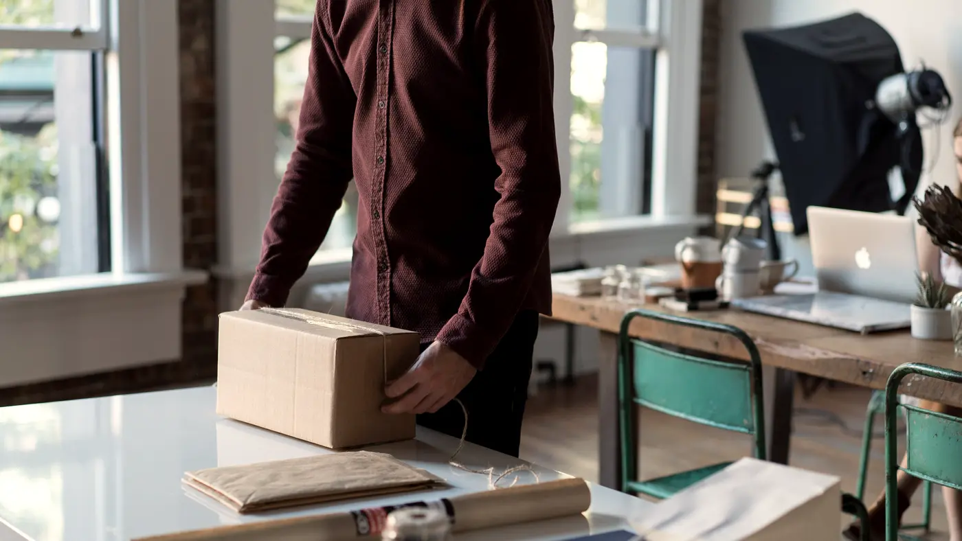 Small business owner packing a cardboard box in a sunny studio
