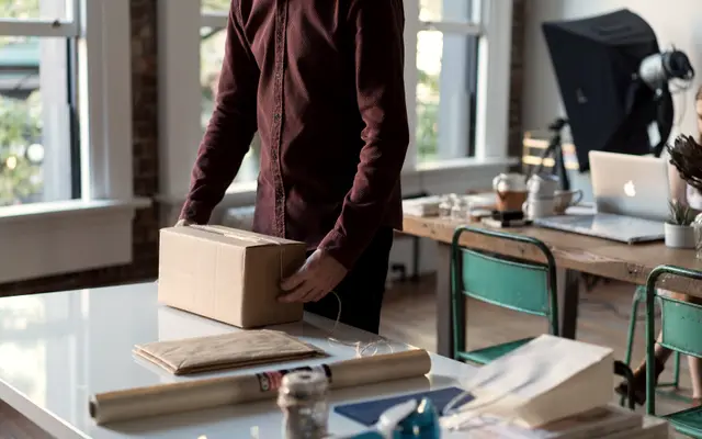 Small business owner packing a cardboard box in a sunny studio
