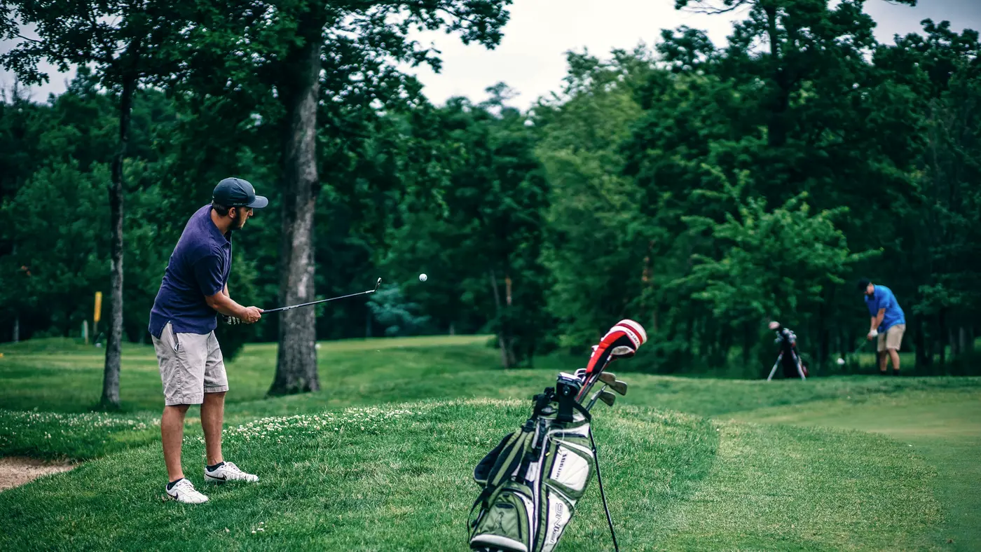 Golfers playing on a green tree-lined course