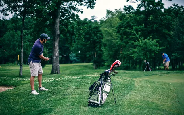 Golfers playing on a green tree-lined course