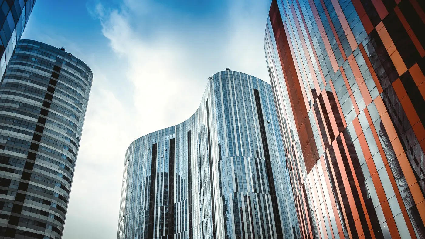 Curved glass office towers against a bright blue sky