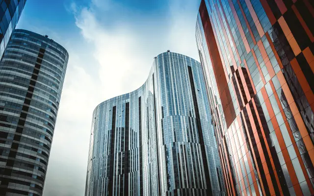 Curved glass office towers against a bright blue sky