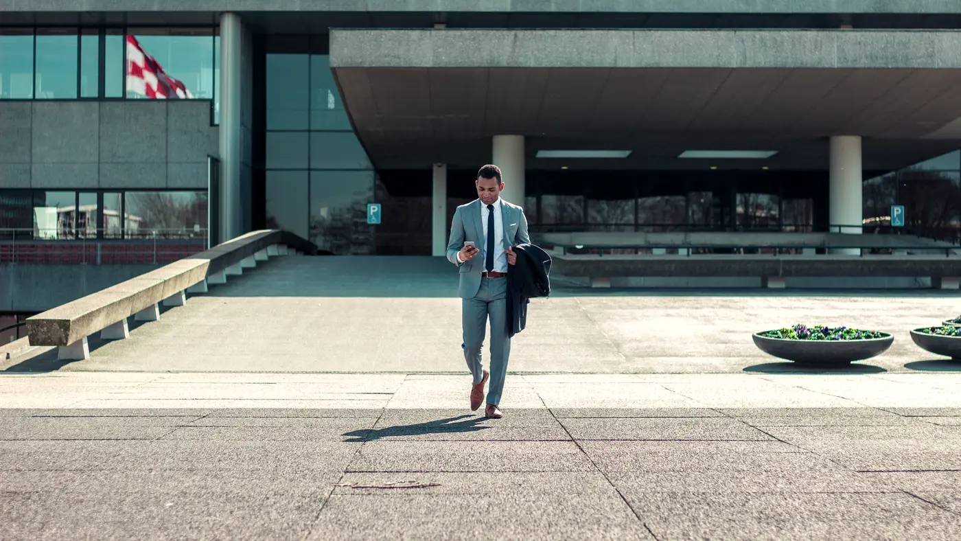 Businessman in a suit walking out of a modern building