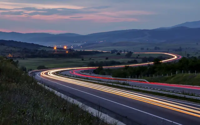 Car light trails on a curving highway at dusk