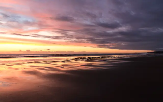 Calm beach at dusk under pink and purple clouds