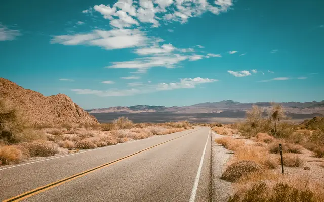 Empty desert highway under a bright blue sky