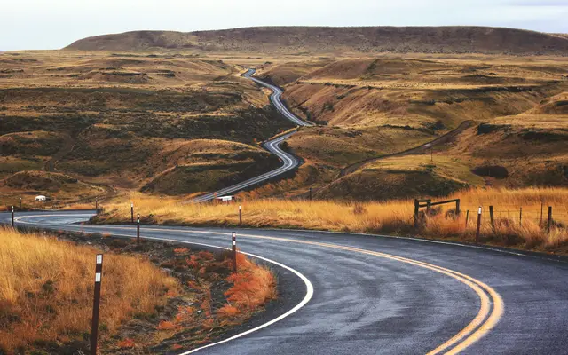 Winding road snaking through golden grassland hills