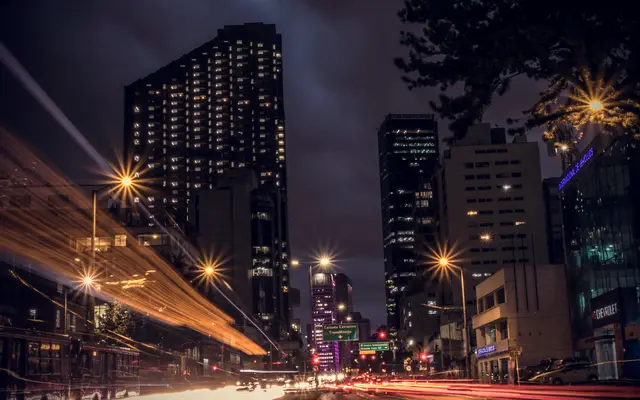 Downtown high-rises at night with streetlights and traffic light trails