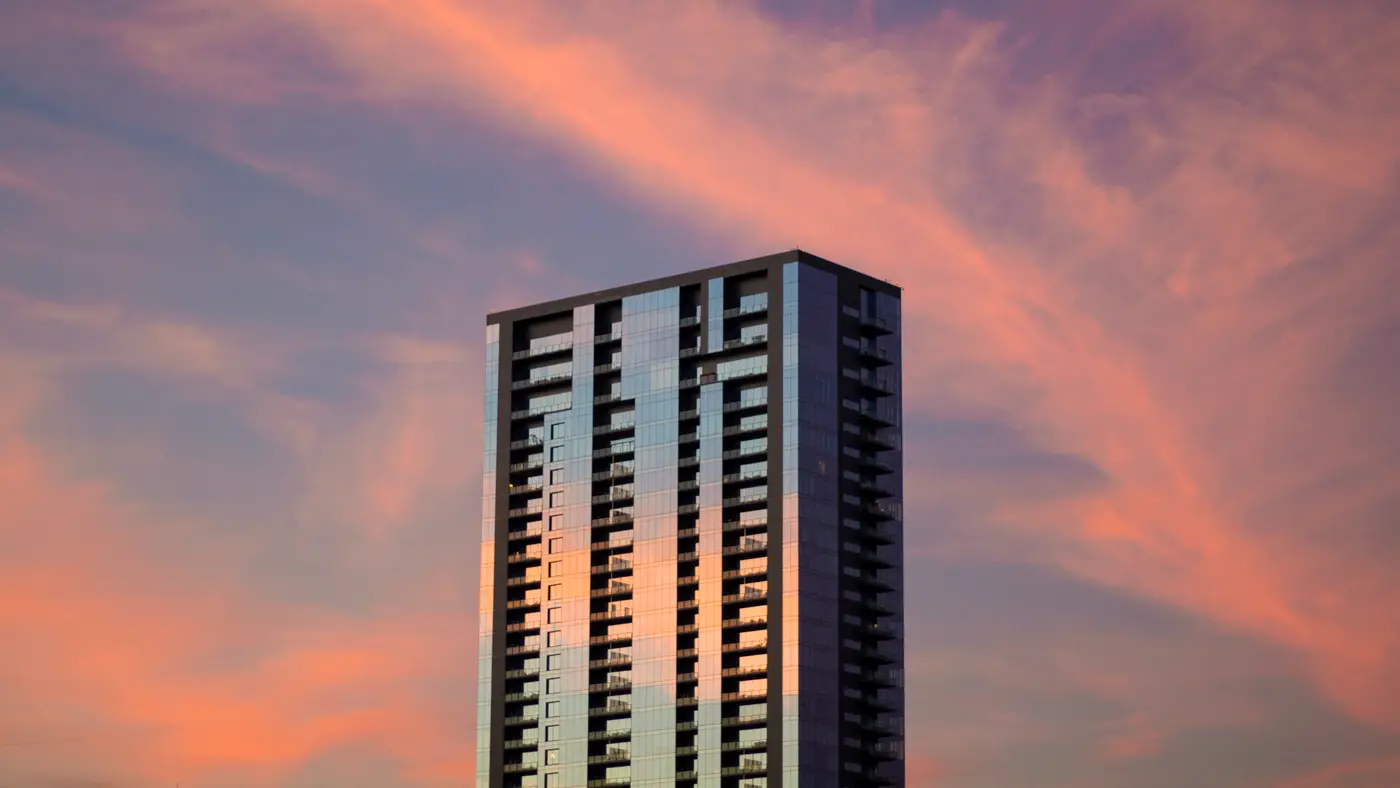 High-rise tower against a pink and purple sunset sky