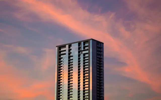 High-rise tower against a pink and purple sunset sky