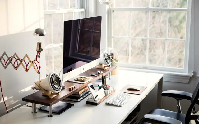 Home office desk with monitor beside tall sash windows