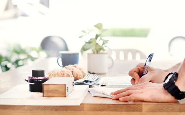 Hand writing on paper at a bright tidy desk