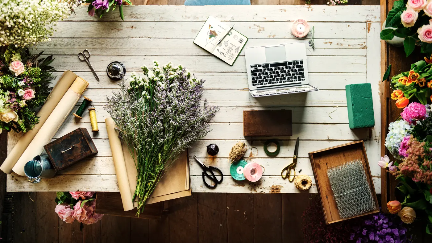 Florist workbench with laptop, cut flowers, scissors and wrapping paper