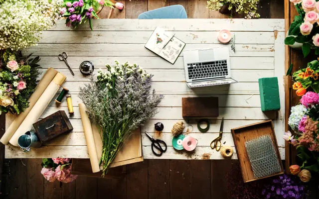 Florist workbench with laptop, cut flowers, scissors and wrapping paper