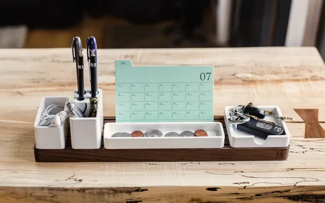 Wooden desk organiser holding pens, keys and a small calendar