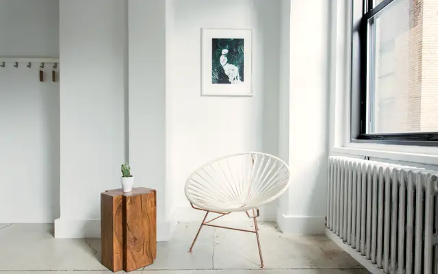 Bright empty white room with a single chair by the window