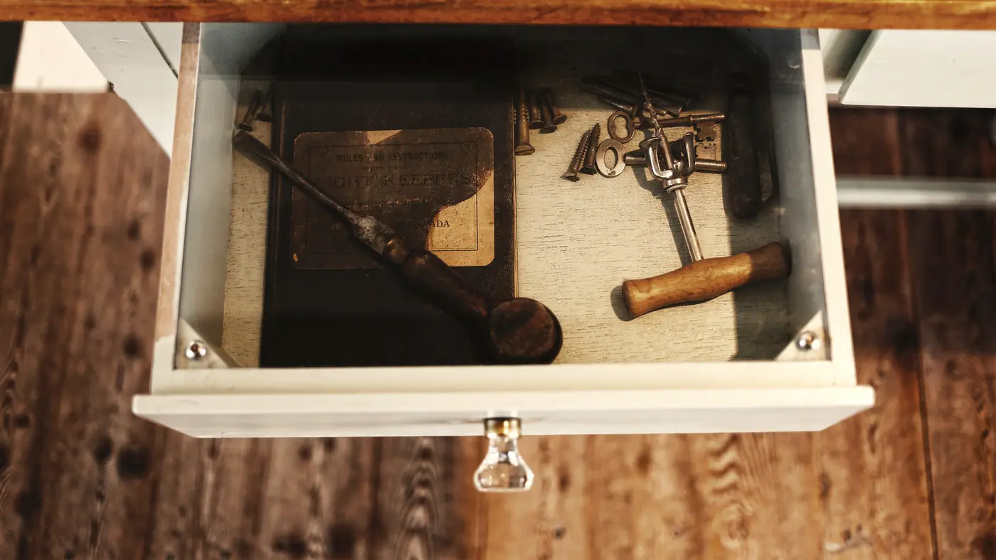 Open drawer holding an old hammer and hand tools