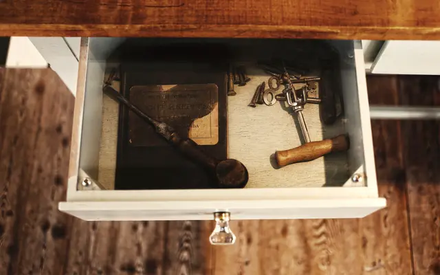 Open drawer holding an old hammer and hand tools