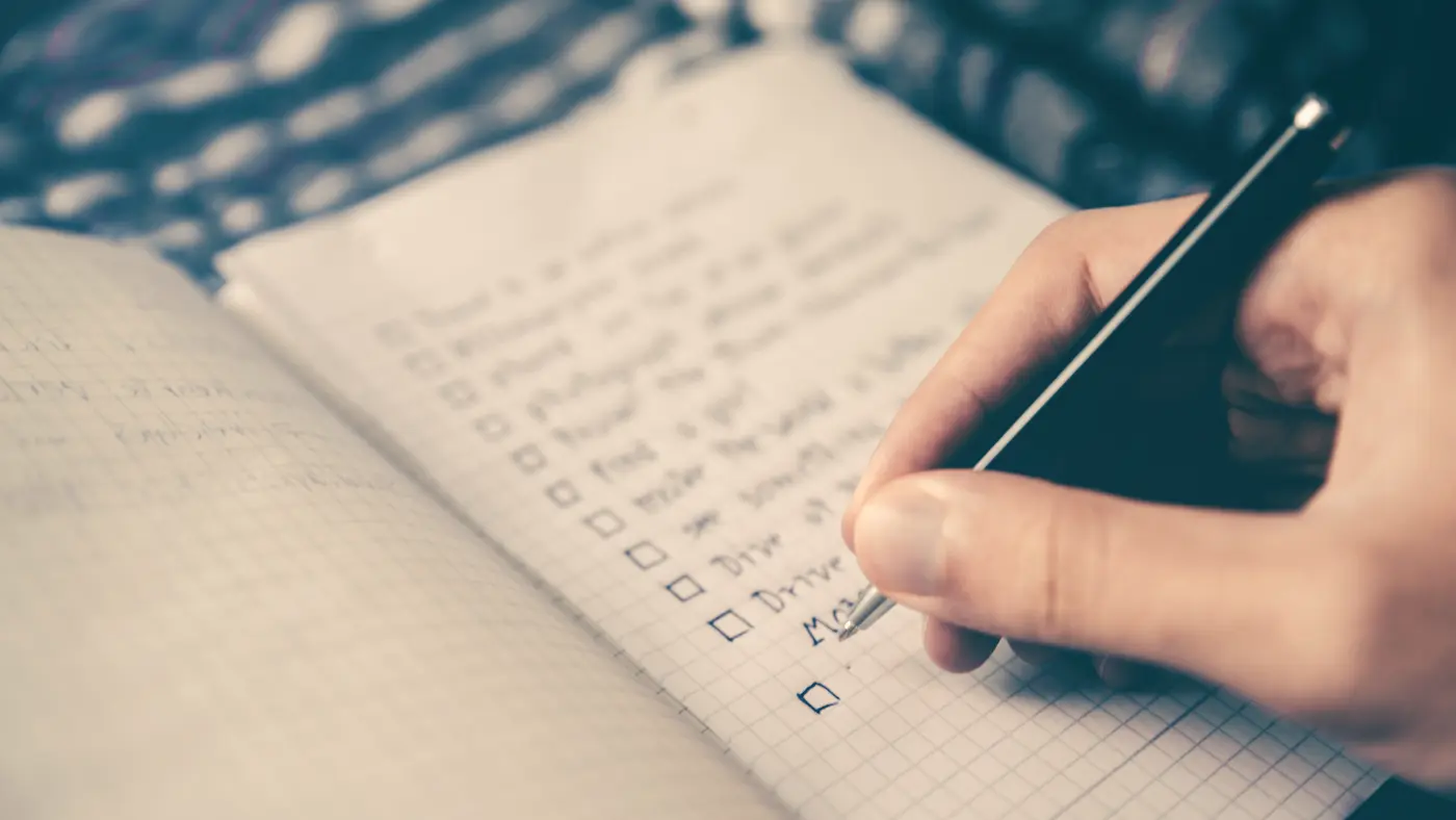 Hand writing a checklist in an open notebook