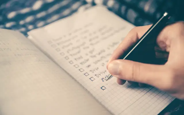 Hand writing a checklist in an open notebook