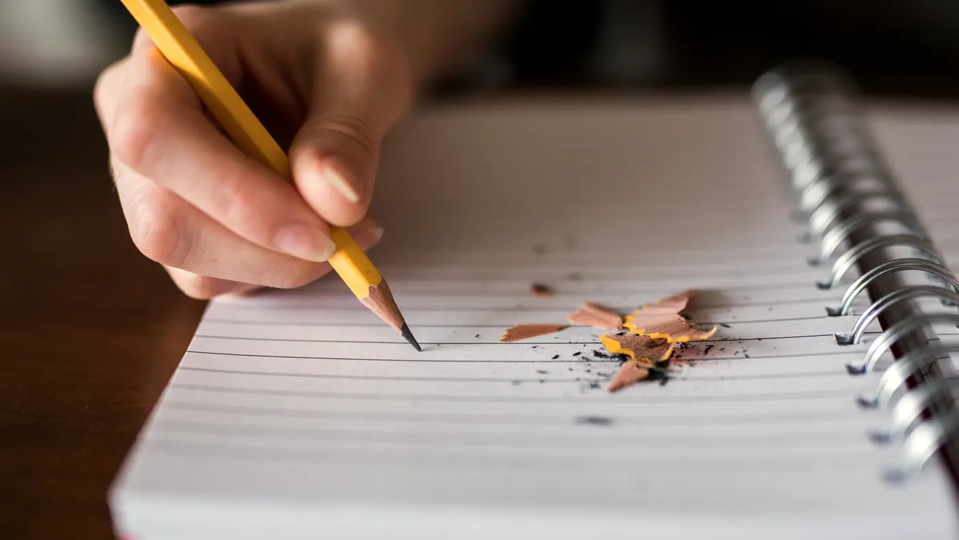 Hand writing with a pencil in a spiral notebook