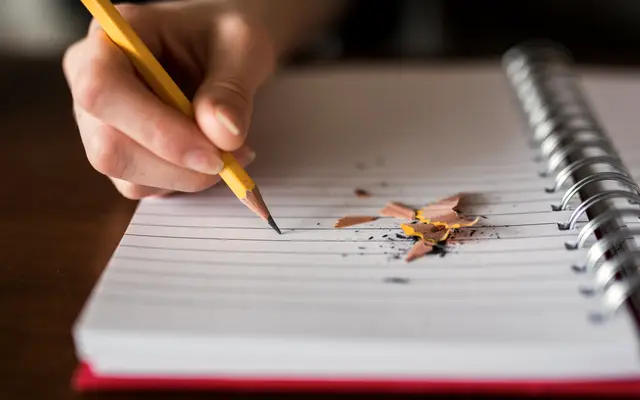 Hand writing with a pencil in a spiral notebook