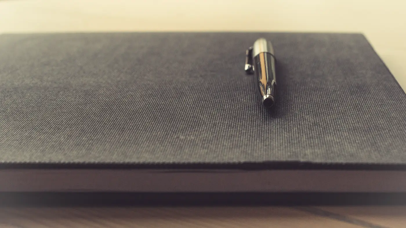 Silver pen resting on a closed grey notebook