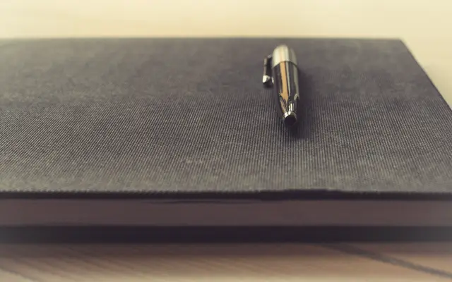 Silver pen resting on a closed grey notebook