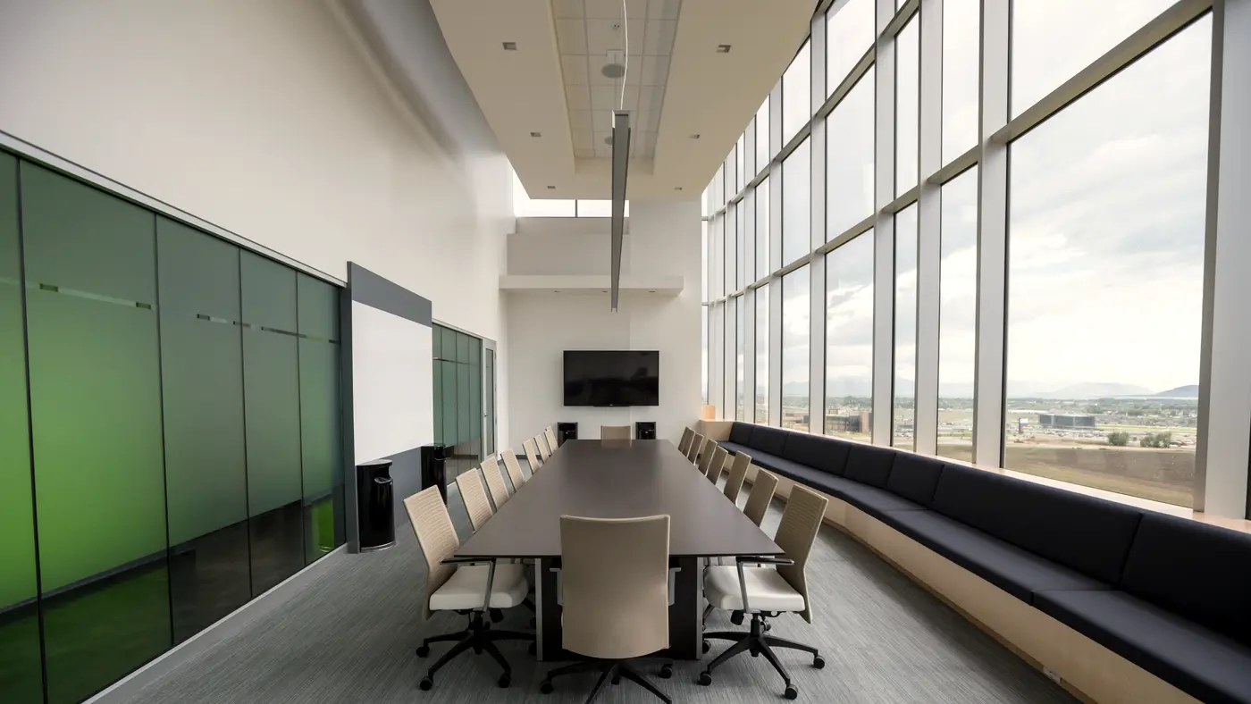 Long boardroom table beside a wall of floor to ceiling windows