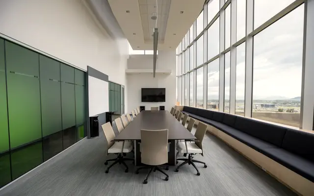 Long boardroom table beside a wall of floor to ceiling windows