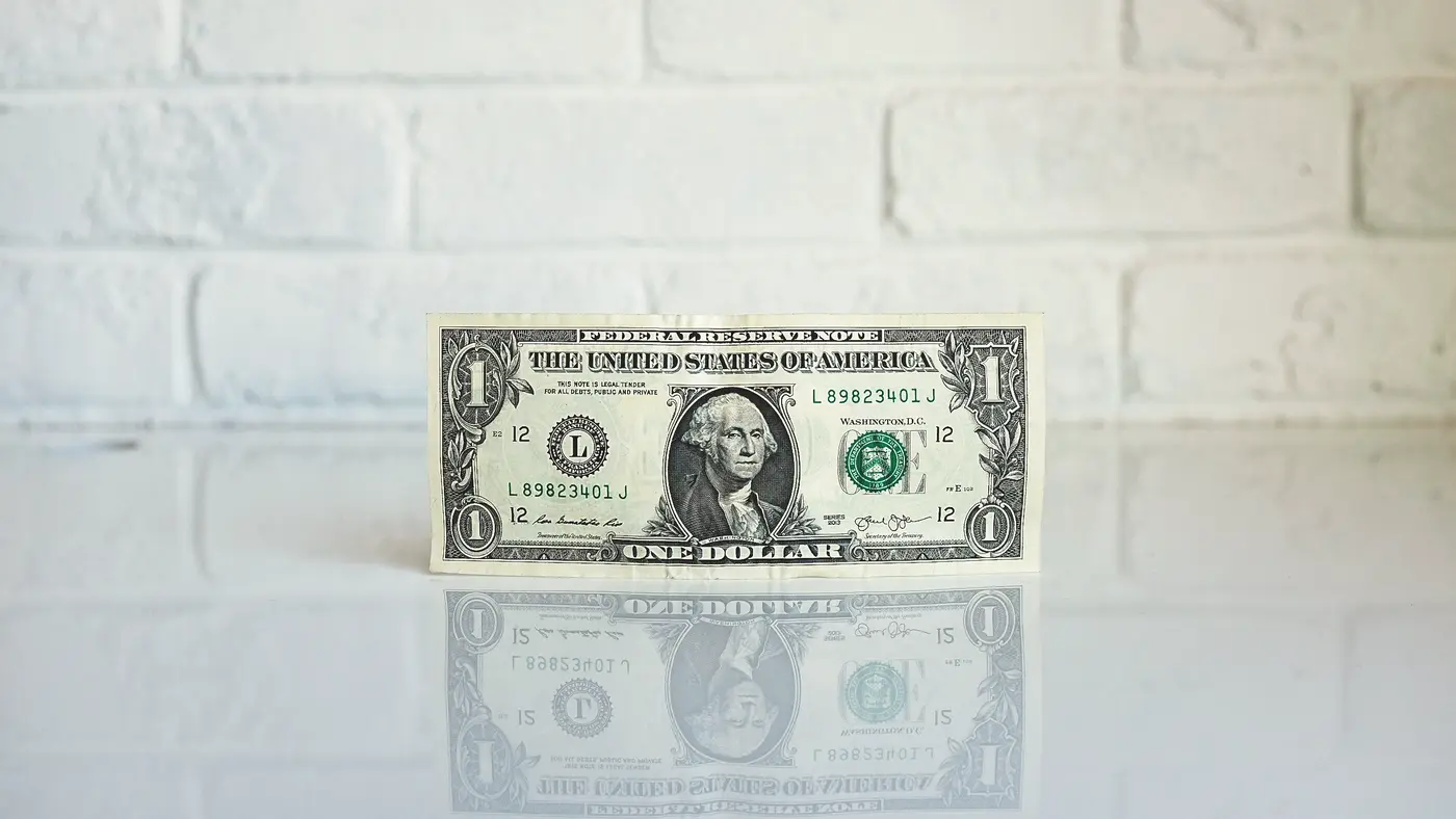 Single one-dollar bill standing upright on a white table
