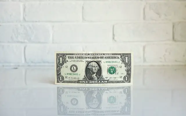 Single one-dollar bill standing upright on a white table