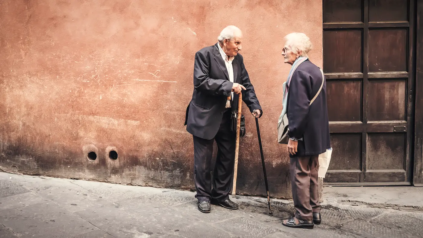 Two elderly men in suits talking on a quiet street