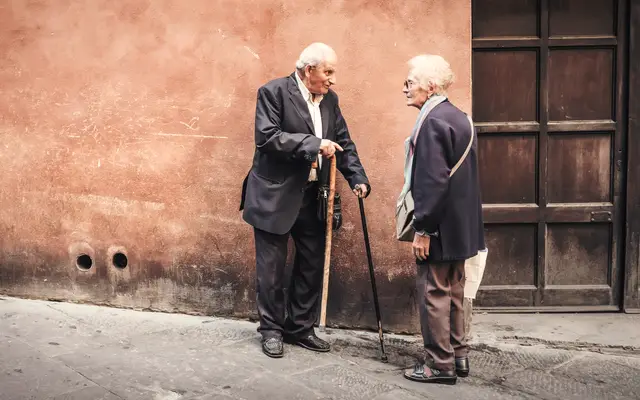 Two elderly men in suits talking on a quiet street