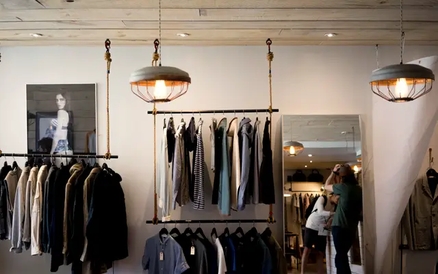 Bright independent clothing shop with pendant lamps and a customer