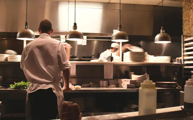 Cook working at the pass of a busy restaurant kitchen