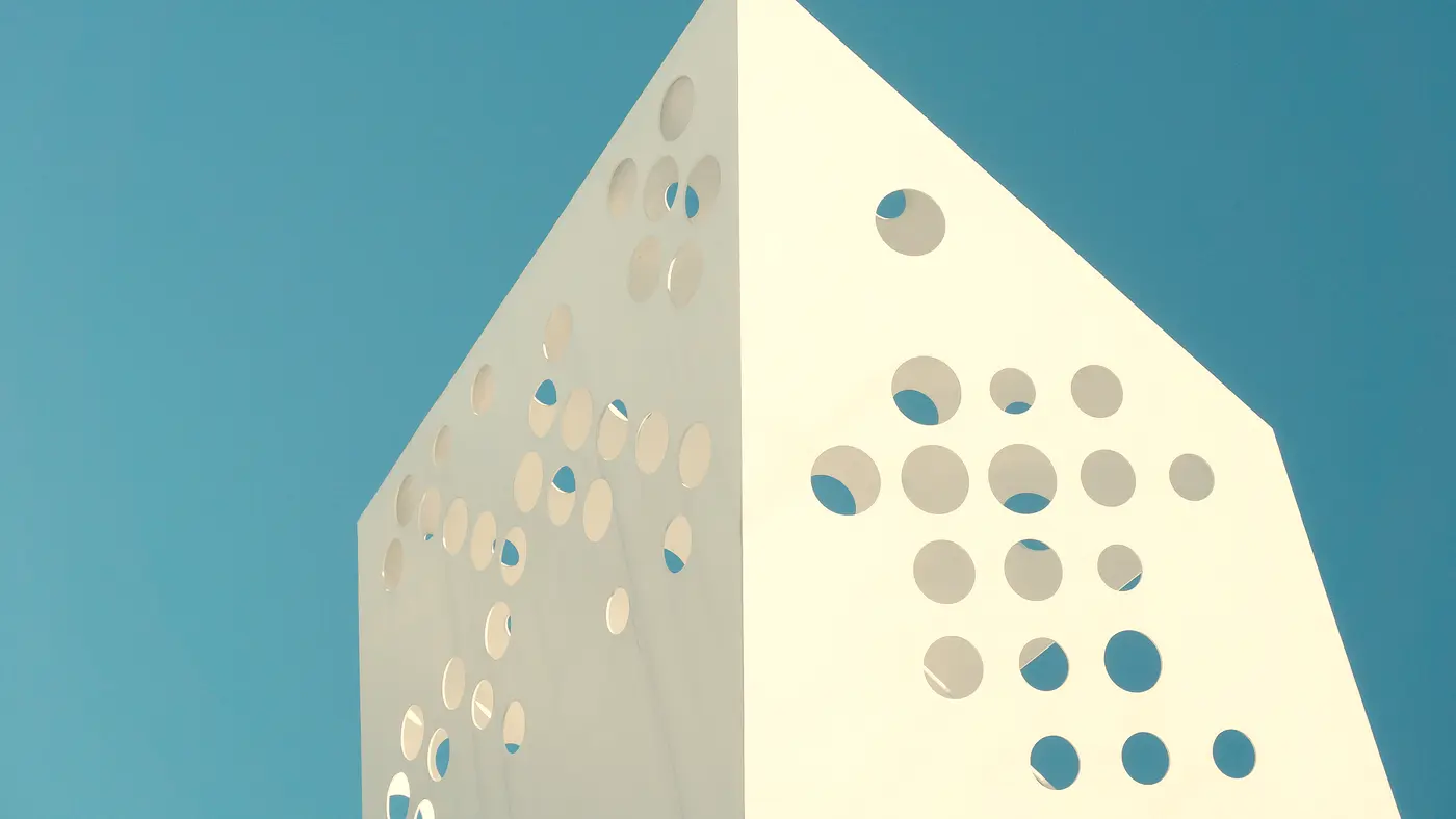 White modern building with round cutouts against a teal sky