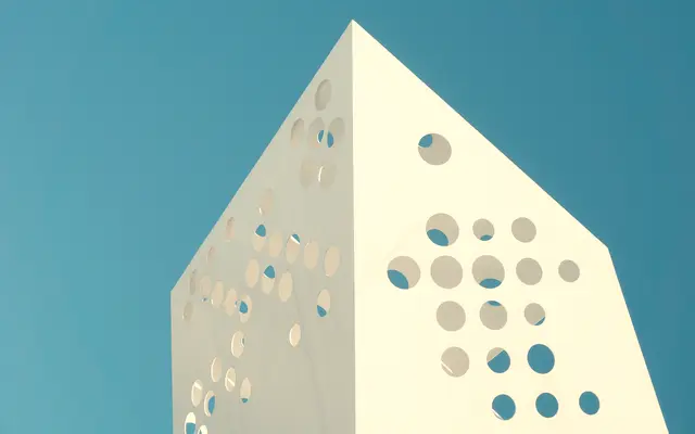 White modern building with round cutouts against a teal sky