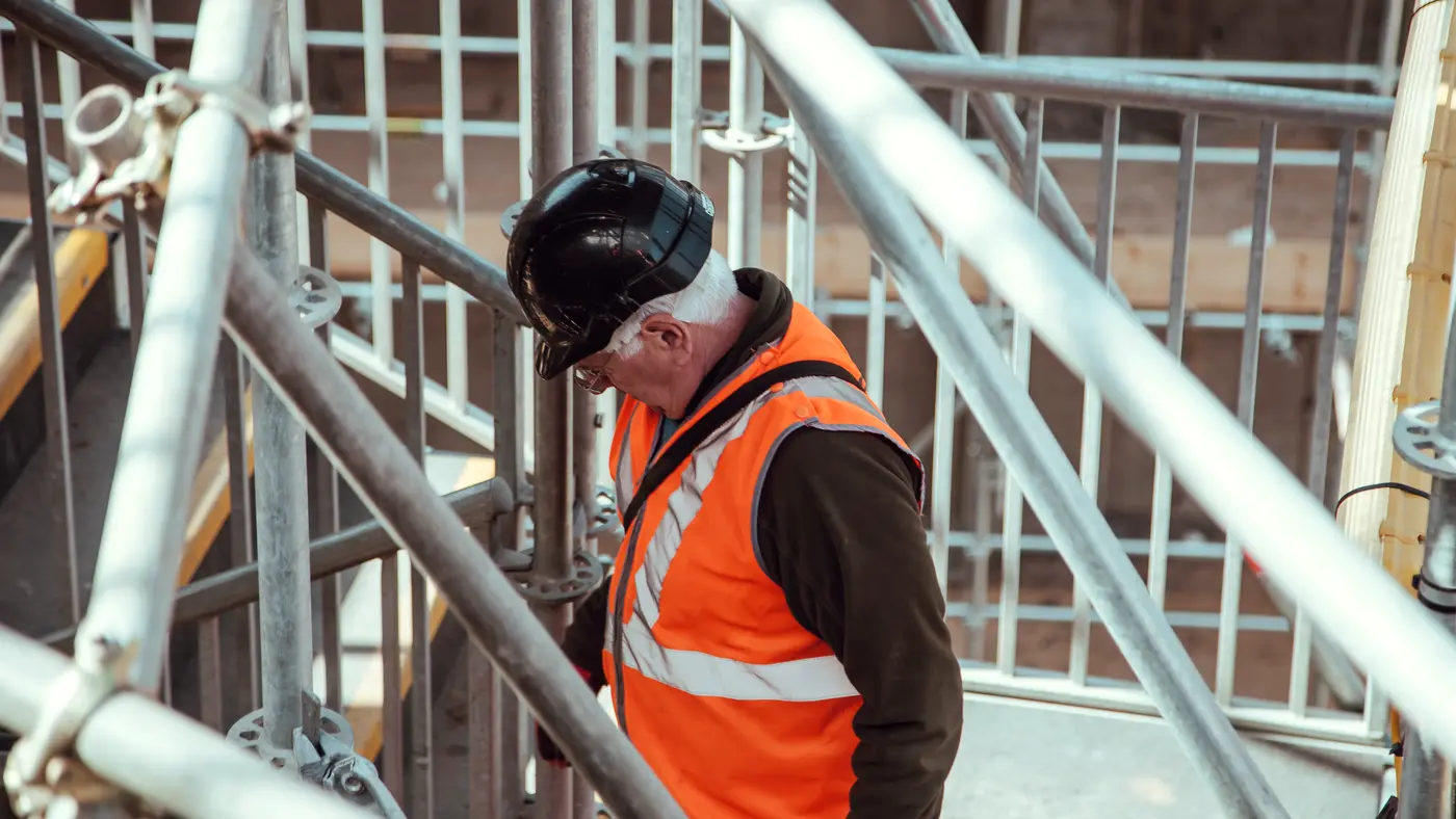 Construction worker in hard hat and safety vest on scaffolding