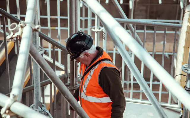 Construction worker in hard hat and safety vest on scaffolding