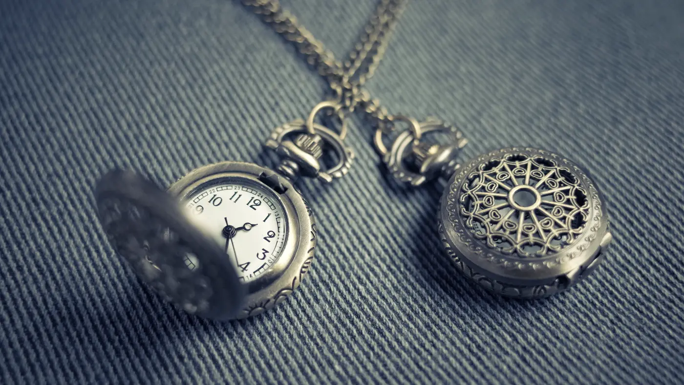 Two antique pocket watches resting on dark denim fabric