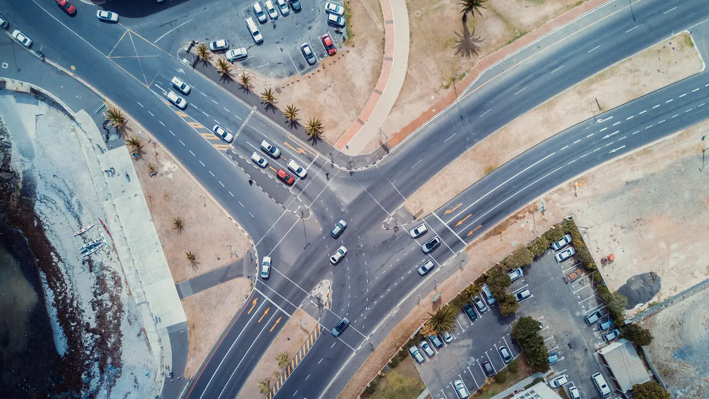 Aerial view of a busy road intersection with cars and parking lots