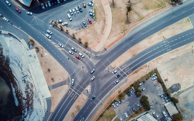 Aerial view of a busy road intersection with cars and parking lots