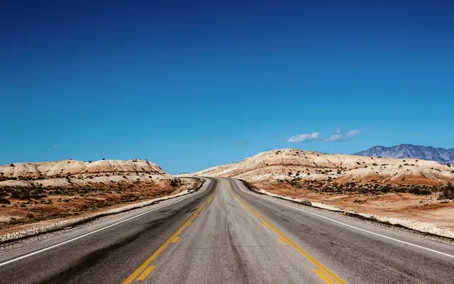 Open desert highway running between pale eroded hills