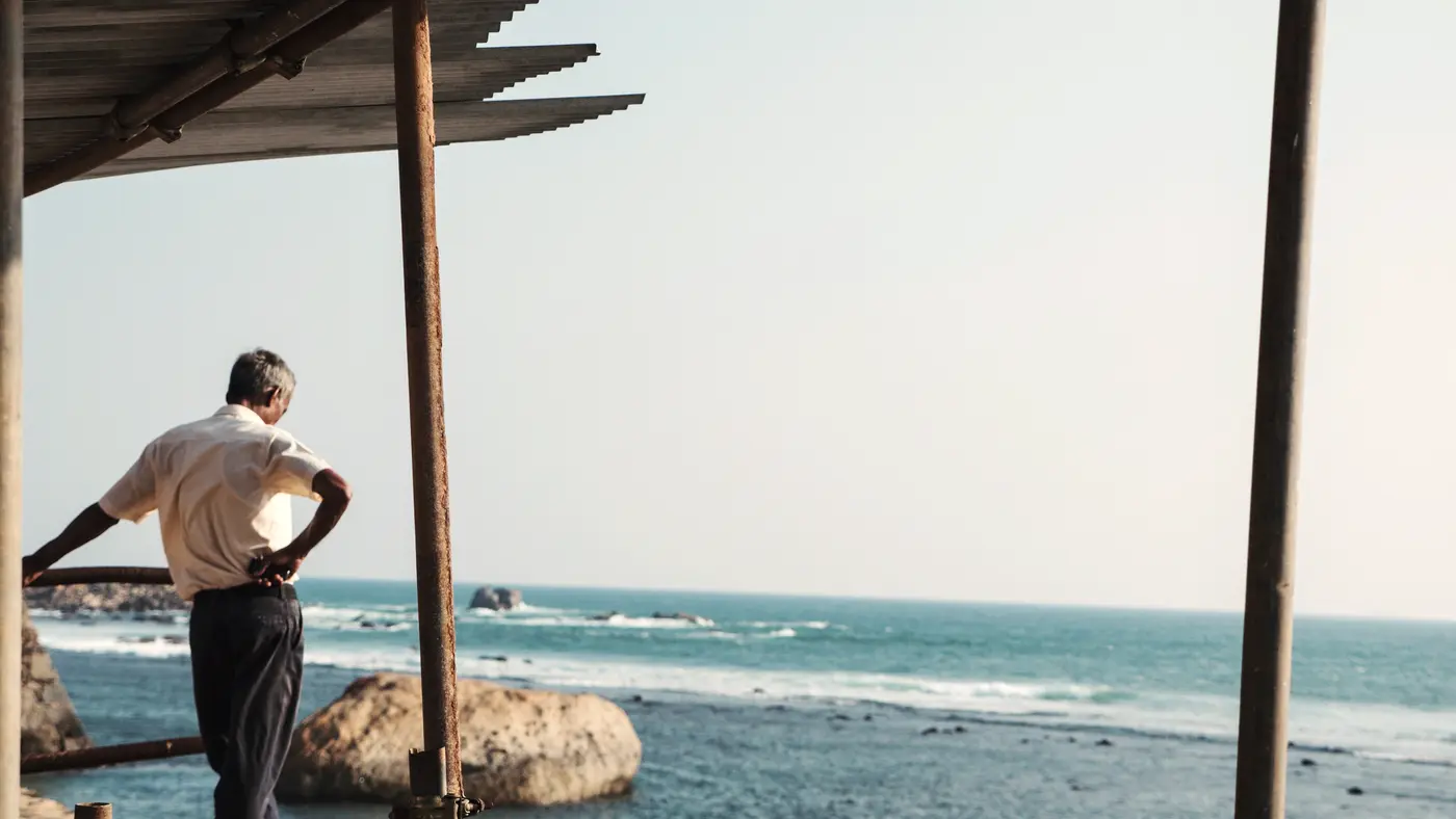 Older man leaning on a railing looking out at the sea