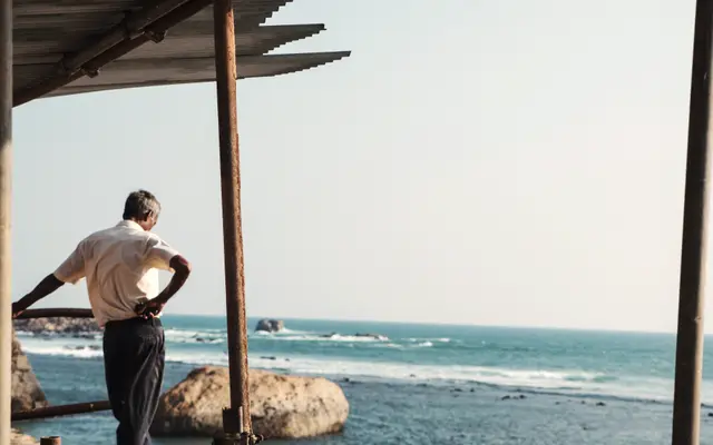 Older man leaning on a railing looking out at the sea