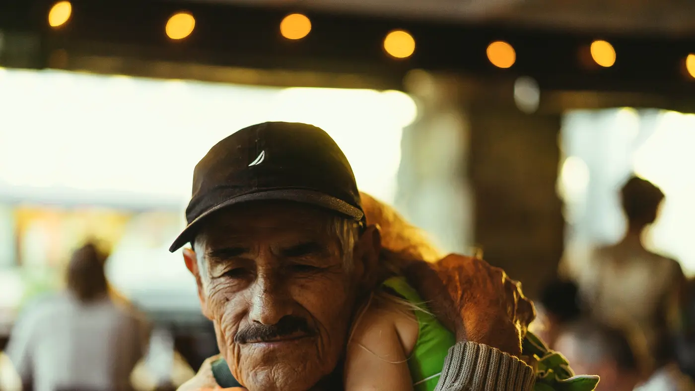 Grandfather in a cap smiling as a child hugs him