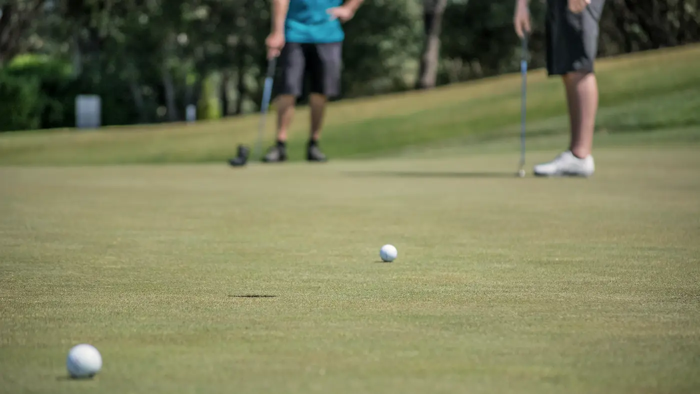 Two golfers putting on a sunny green