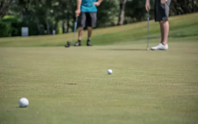 Two golfers putting on a sunny green