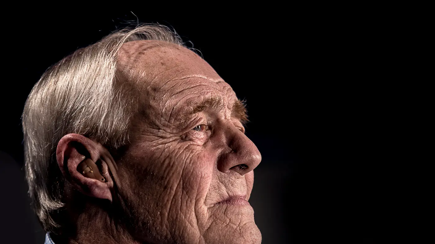 Portrait of a thoughtful older man against a dark background